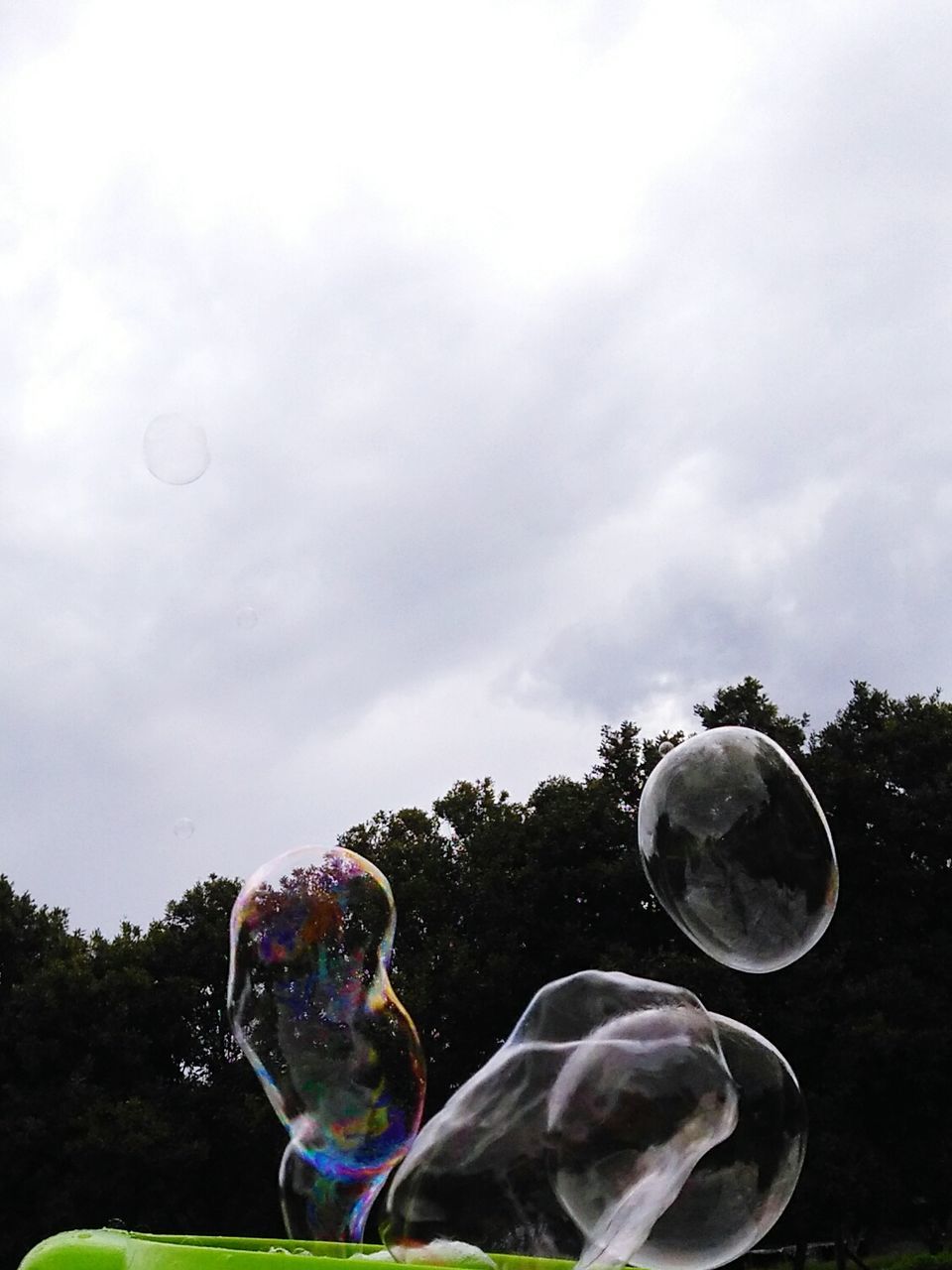 Low angle view of bubbles in mid-air against sky
