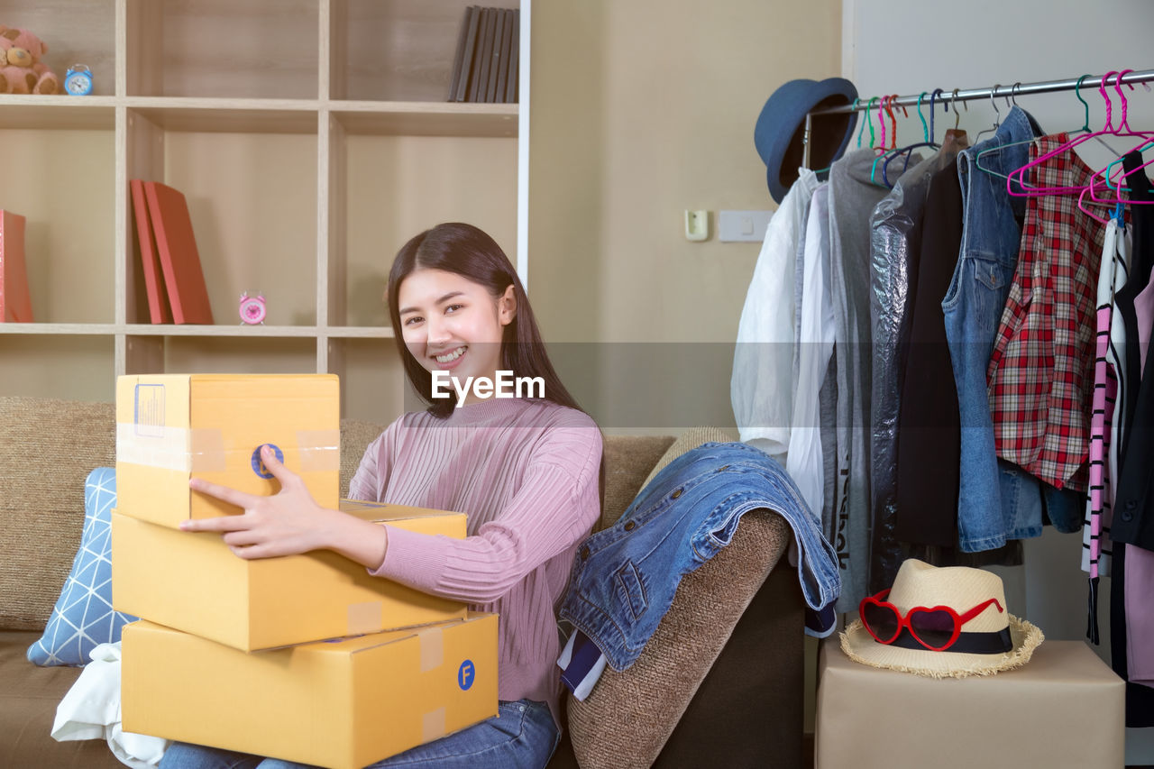 Portrait of smiling young woman with boxes at home