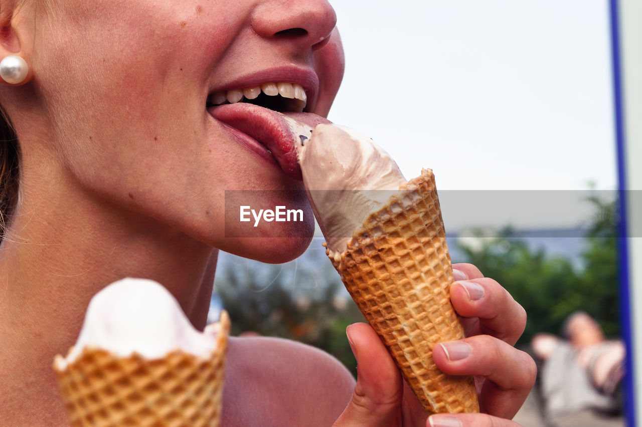 Midsection of woman licking ice cream