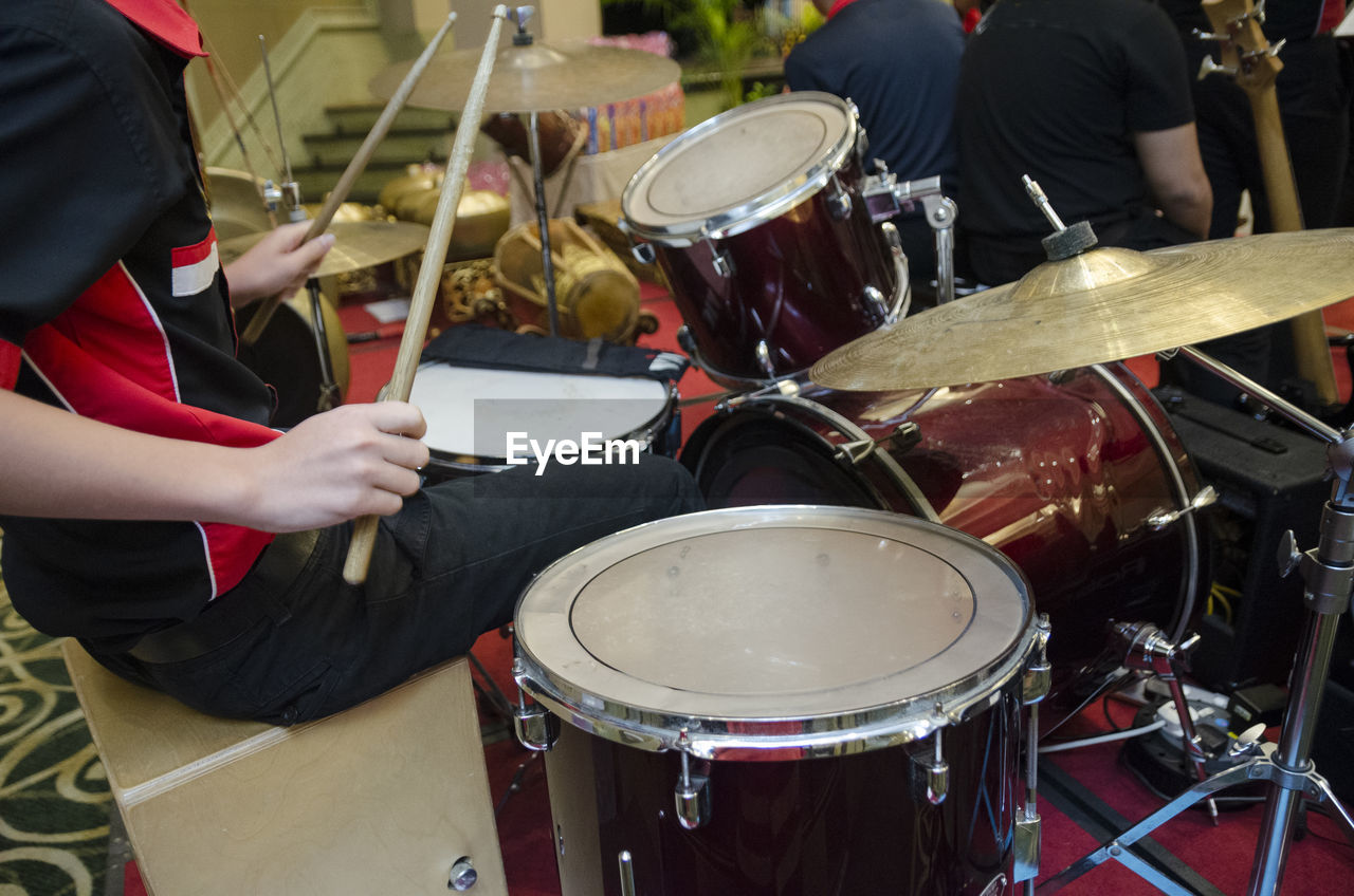 Midsection of musician playing drum kit