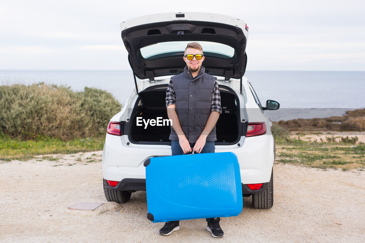 PORTRAIT OF MAN STANDING IN CAR