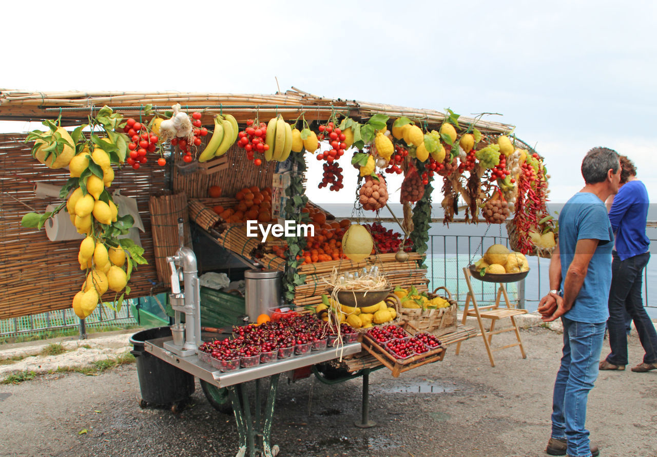 Vendor standing against concession stand selling fruits on roadside