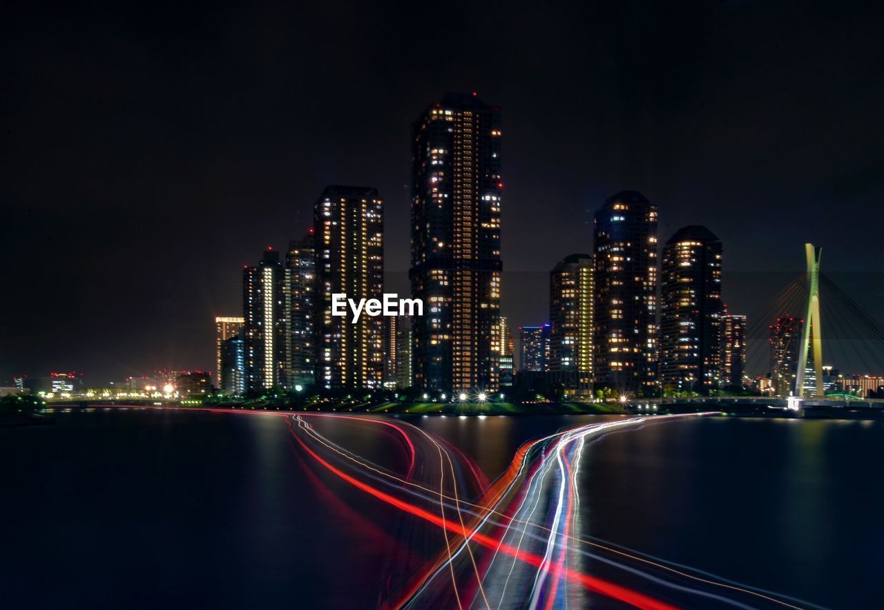 Illuminated modern buildings in city against sky at night