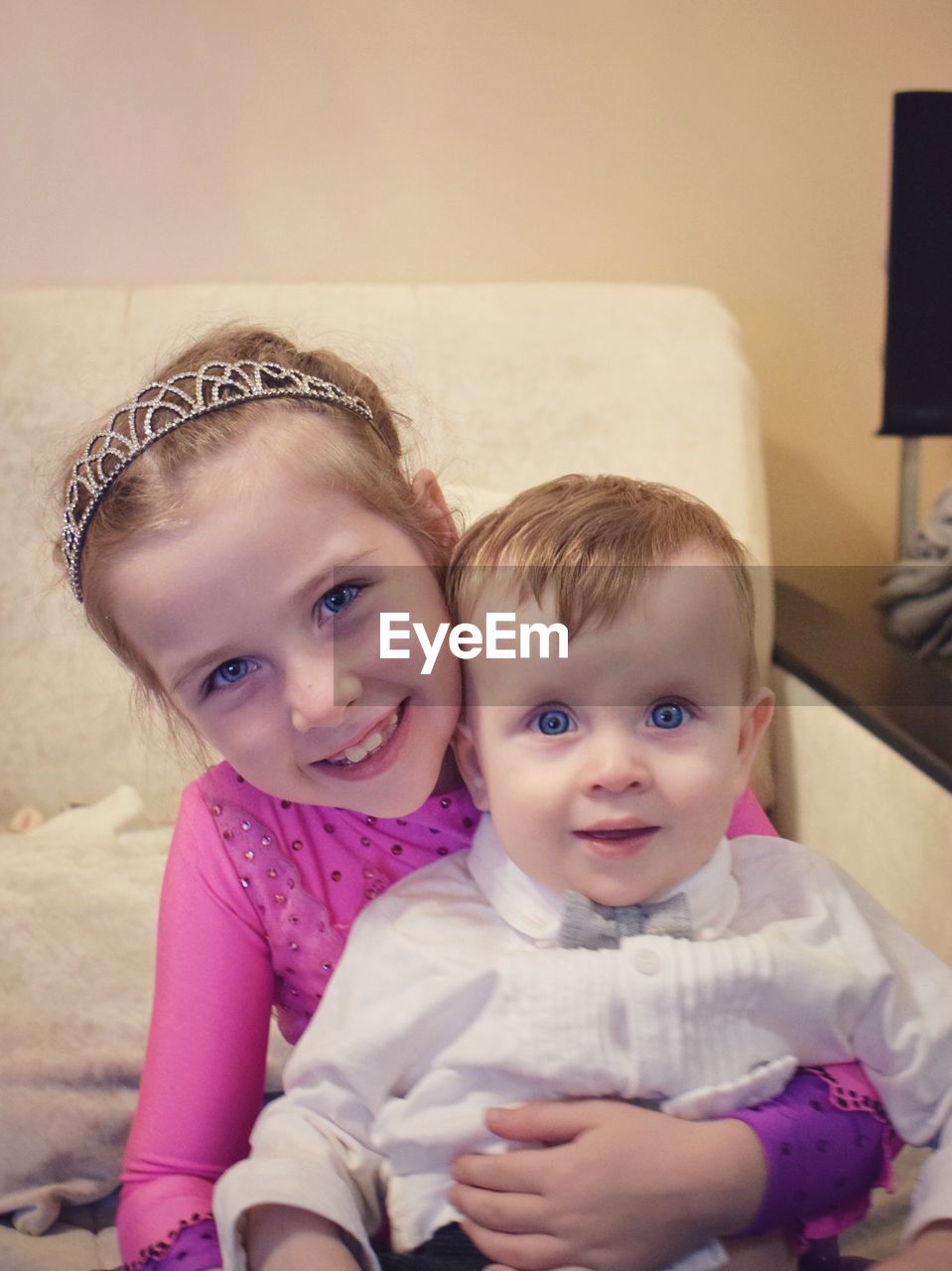 Portrait of smiling sister with brother on sofa at home