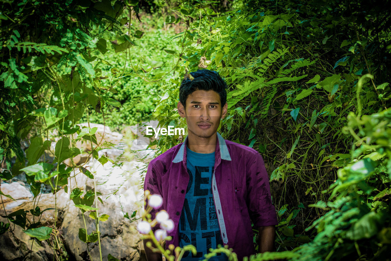 Portrait of young man standing in forest