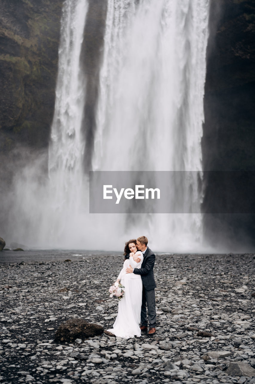 BEAUTIFUL WOMAN STANDING BY WATERFALL