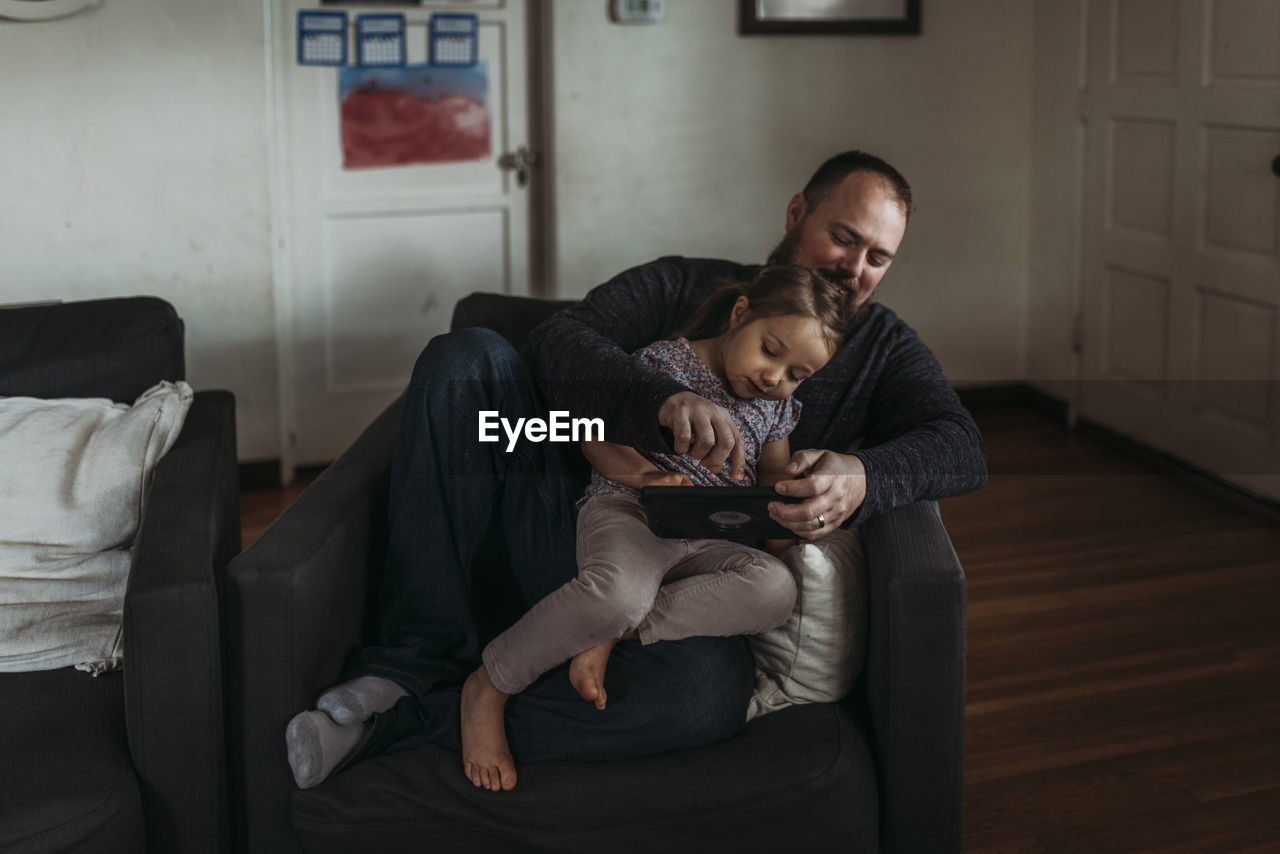 Dad and young daughter playing on tablet during isolation