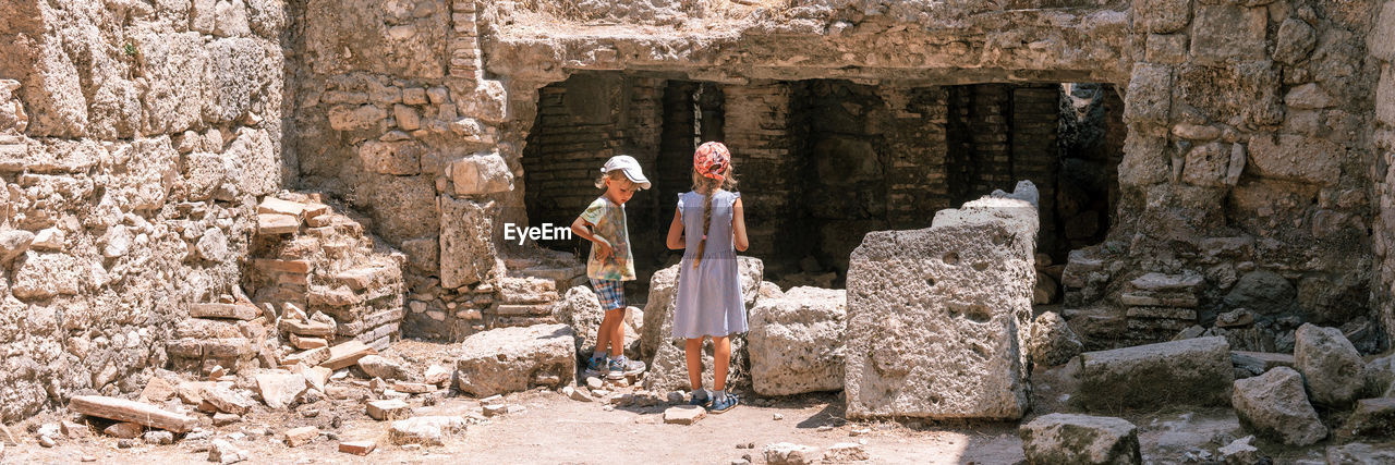 Kids sibling girl and boy travelers travel and explore the ancient excavations of the ruins