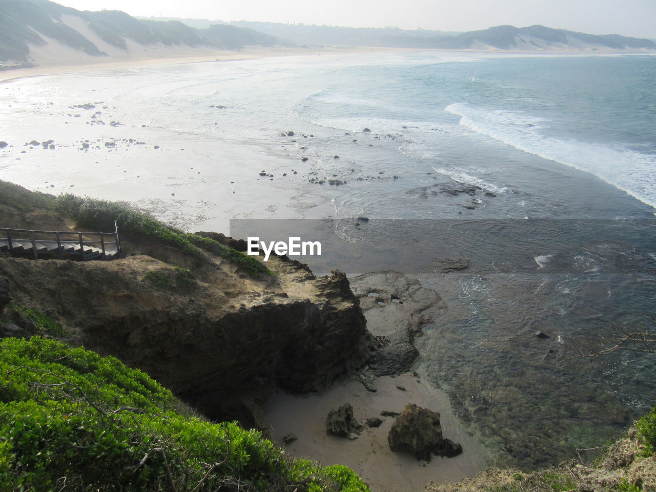 HIGH ANGLE VIEW OF LAND AND SEA AGAINST MOUNTAINS