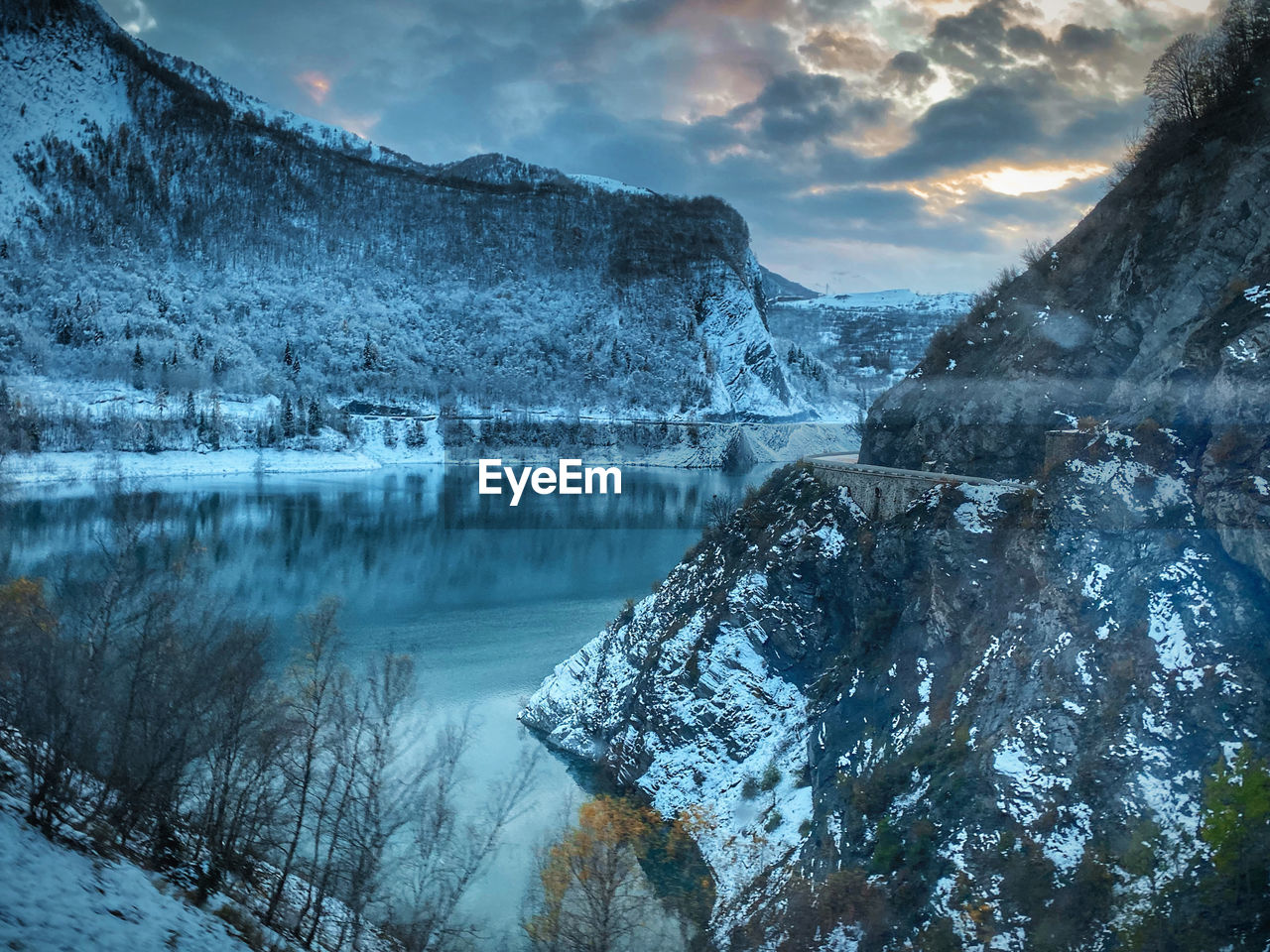 Scenic view of lake by snowcapped mountains against sky