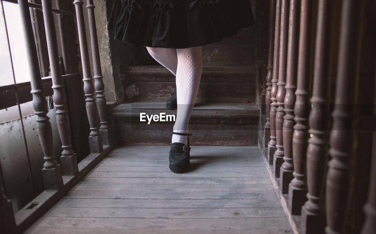 Low section of woman standing on a wooden staircase