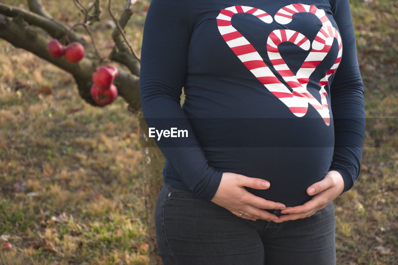 Midsection of pregnant woman standing outdoors
