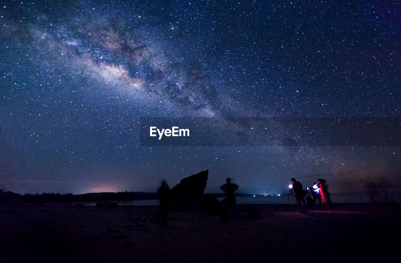 People standing on field against sky at night