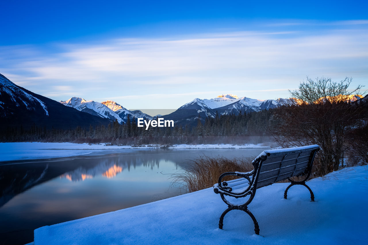 Scenic view of lake by snowcapped mountains against sky