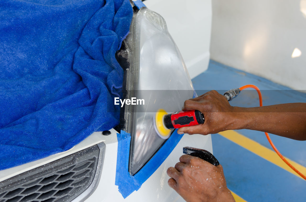 Cropped hand polishing car headlight