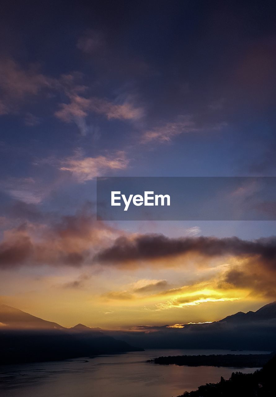 Scenic view of sea against dramatic sky during sunset