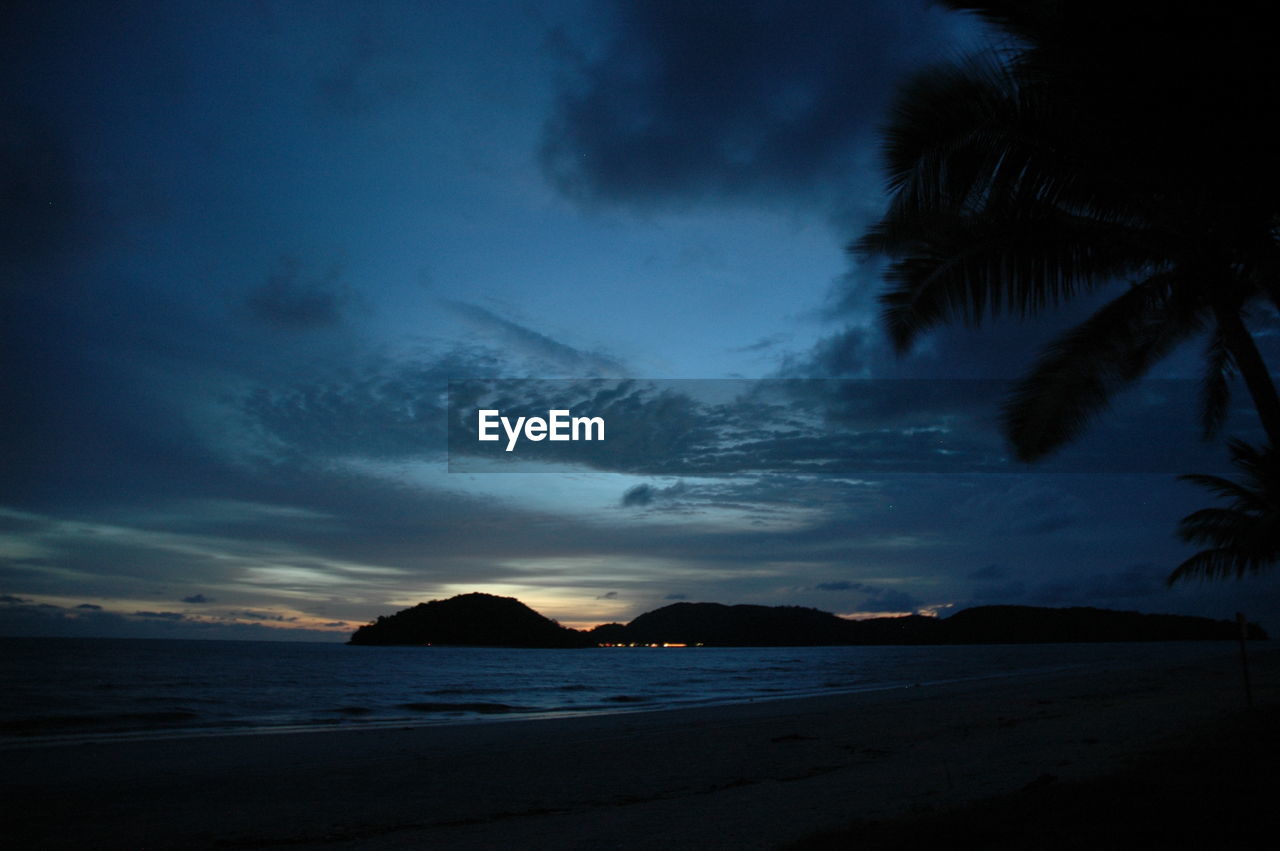 Scenic view of beach against cloudy sky at dusk