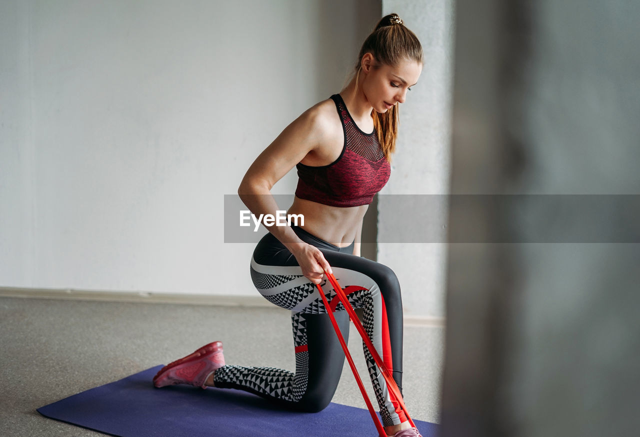 Young woman exercising against wall at home