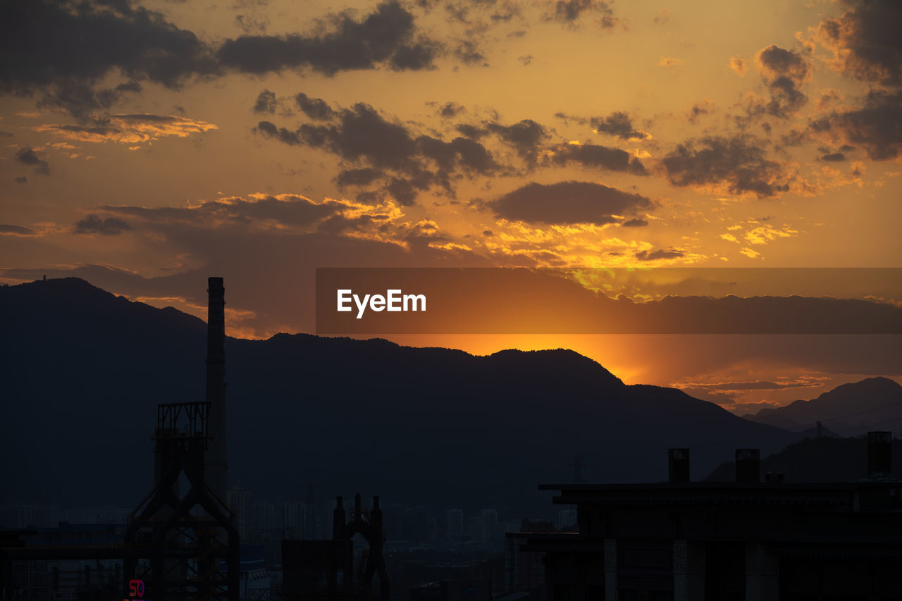 sky, mountain, dawn, sunset, architecture, evening, afterglow, cloud, silhouette, horizon, nature, beauty in nature, built structure, environment, sun, scenics - nature, mountain range, landscape, city, no people, building exterior, travel destinations, outdoors, industry, sunlight, dramatic sky, travel, red sky at morning, building, water, orange color, tranquility