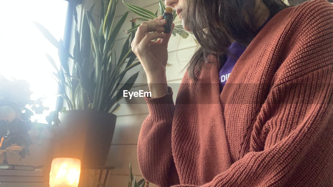 adult, women, one person, lifestyles, nature, person, indoors, young adult, plant, casual clothing, female, sunlight, holding, clothing, hairstyle, waist up, looking, sweater, leisure activity, business finance and industry, standing, business