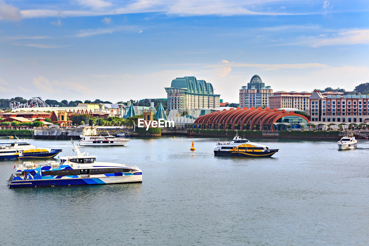 BOATS IN RIVER BY BUILDINGS IN CITY