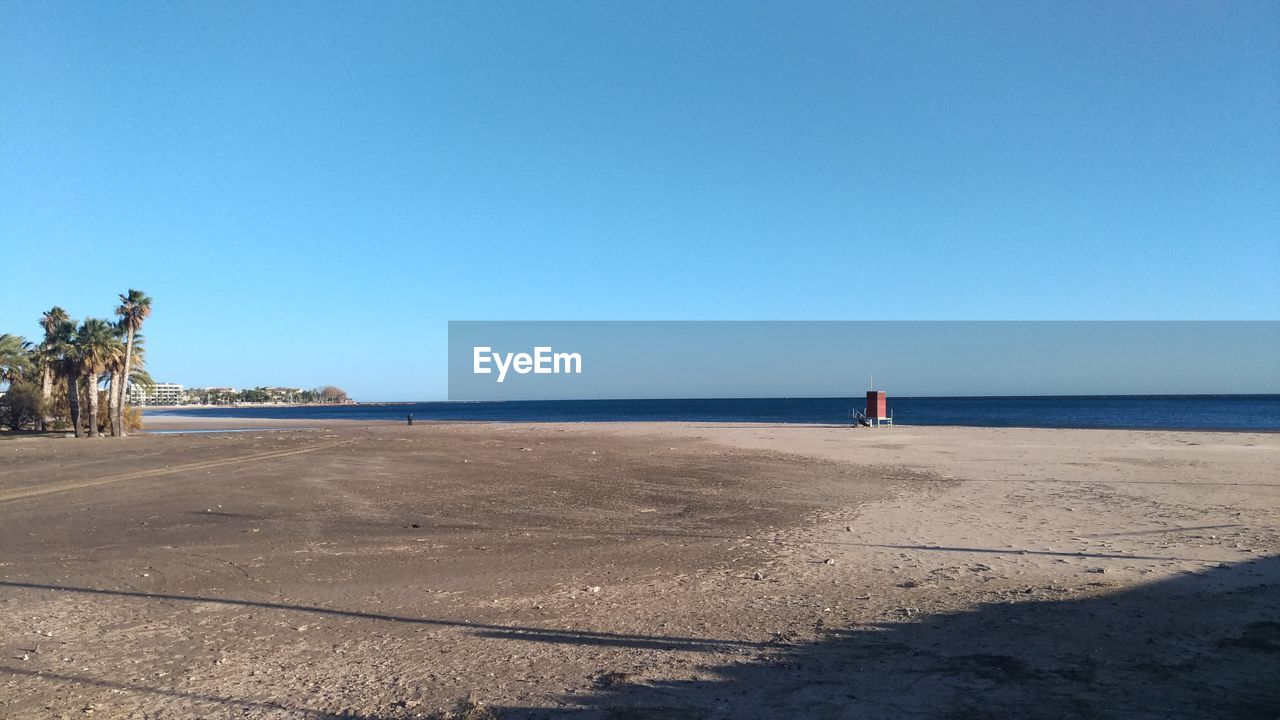 Scenic view of beach against clear blue sky