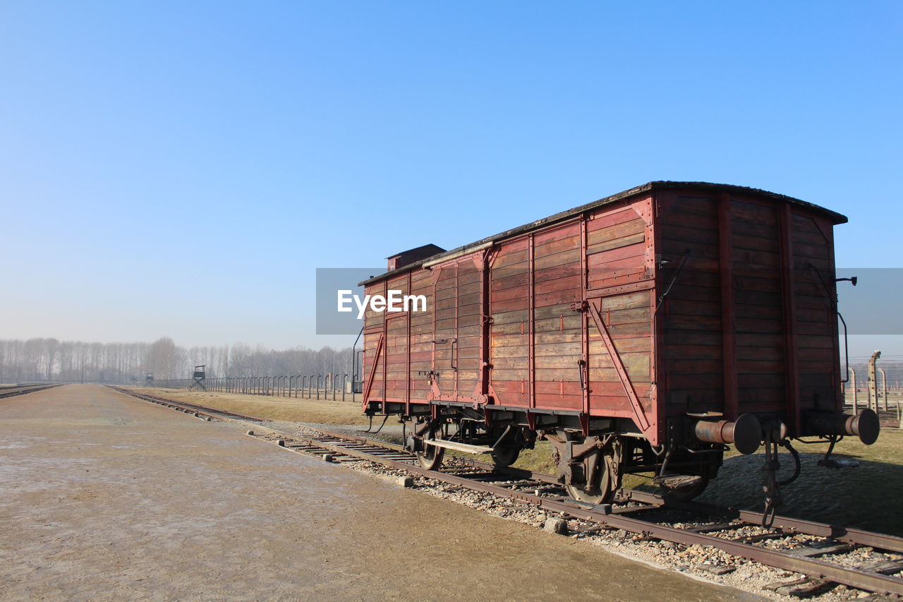 Old abandoned freight train car on track against blue sky