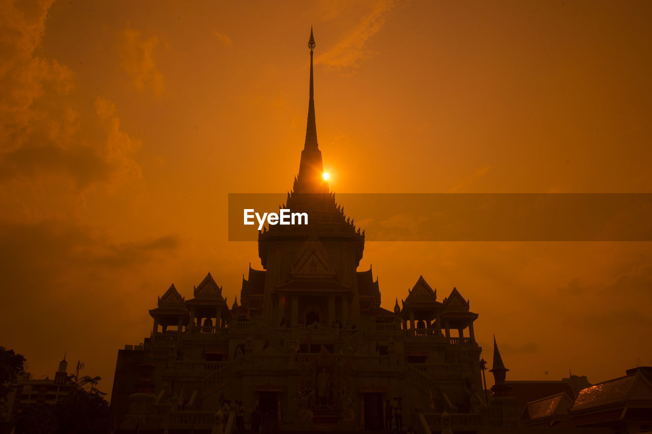 Low angle view of buddhist temple against orange sky