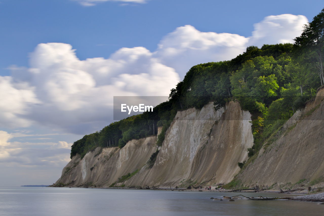 Scenic view of cliff at sea shore against sky