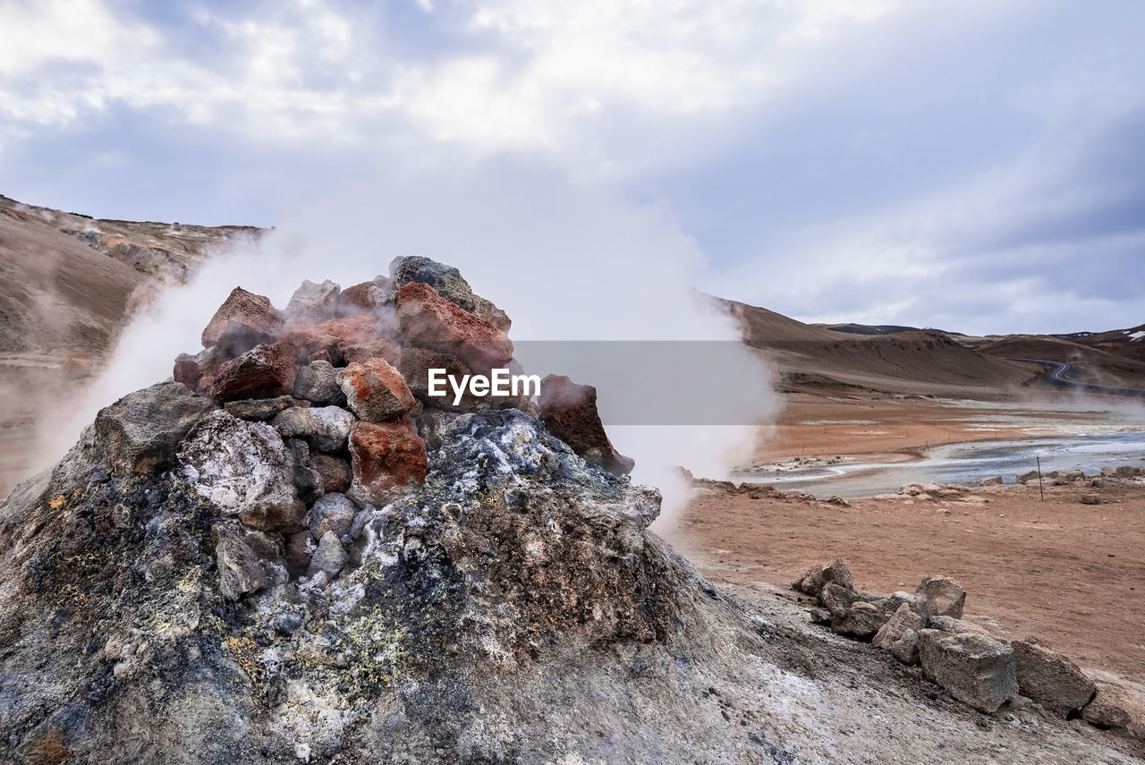 Steaming fumarole in geothermal area of hverir at namafjall against cloudy sky