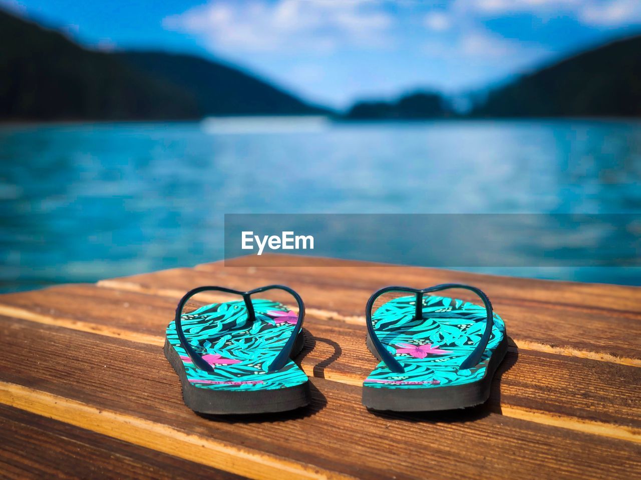 Flip flops on wooden pontoon near the lake