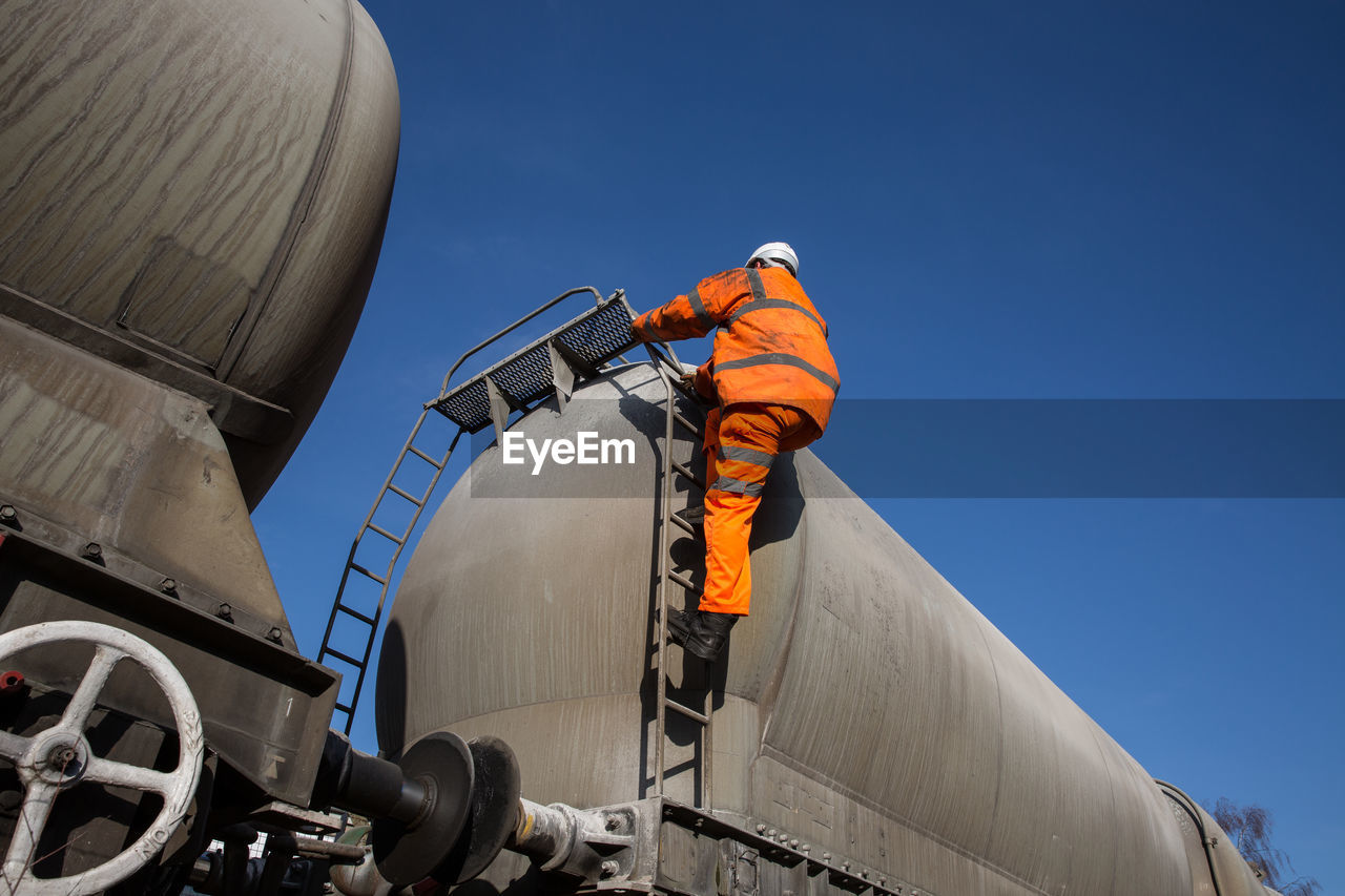 Low angle view of industry against clear blue sky