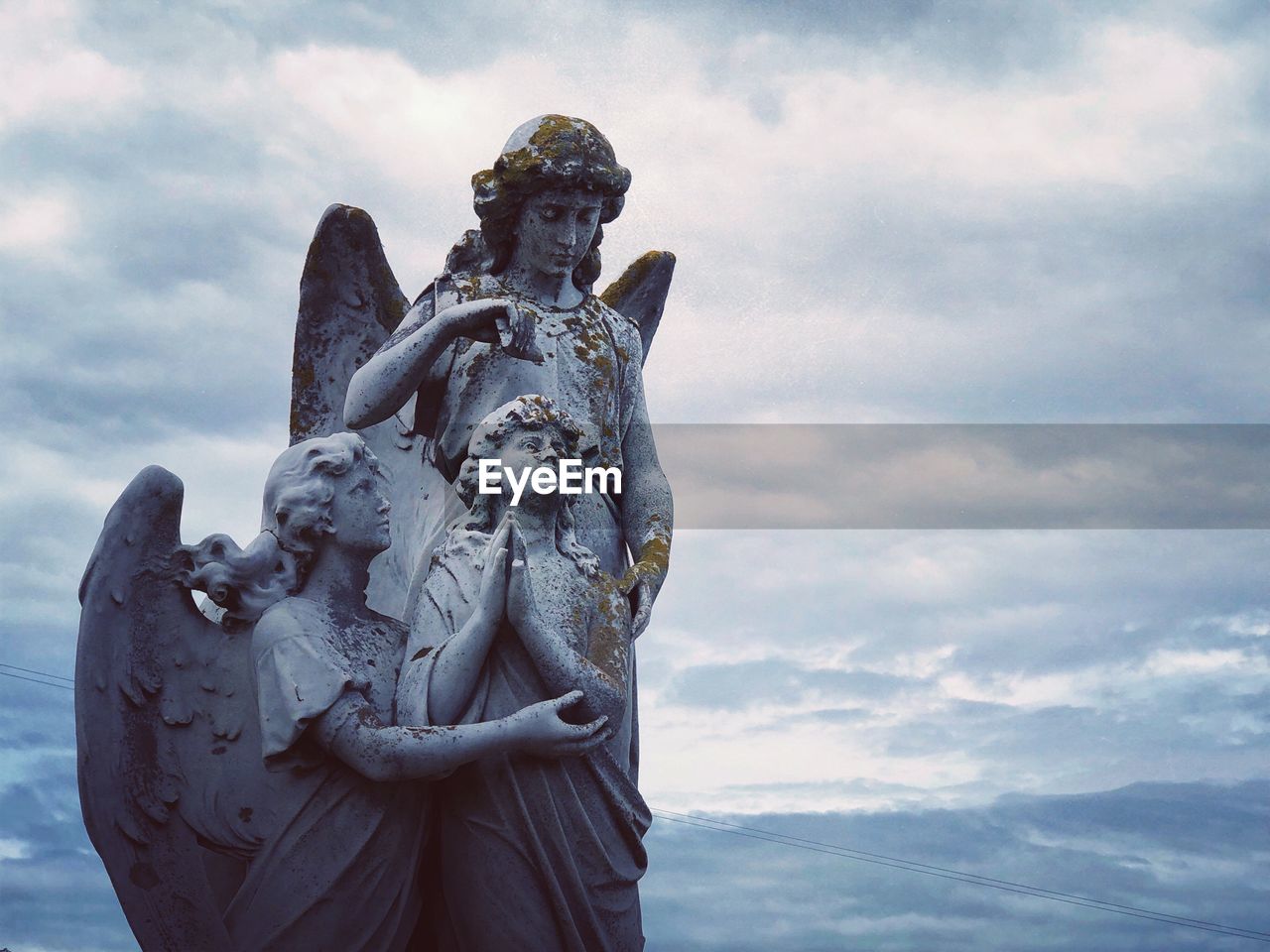 Low angle view of angel statues against sky