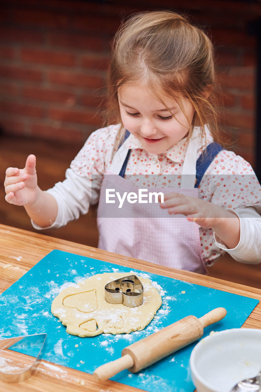 High angle view of cute girl making cookies on table at home