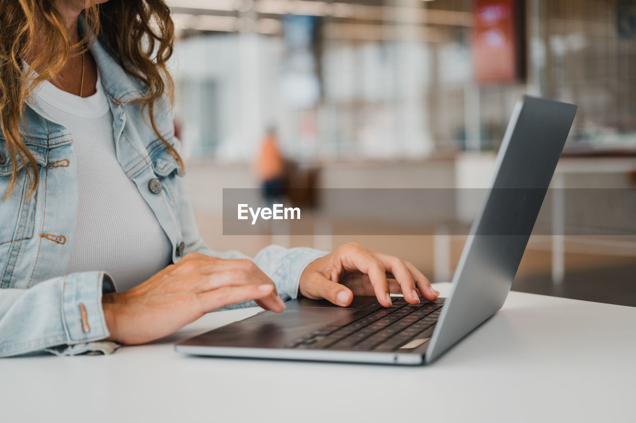 midsection of woman using laptop at desk in office