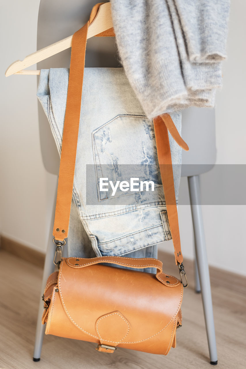 Close-up of purse and jeans hanging on chair