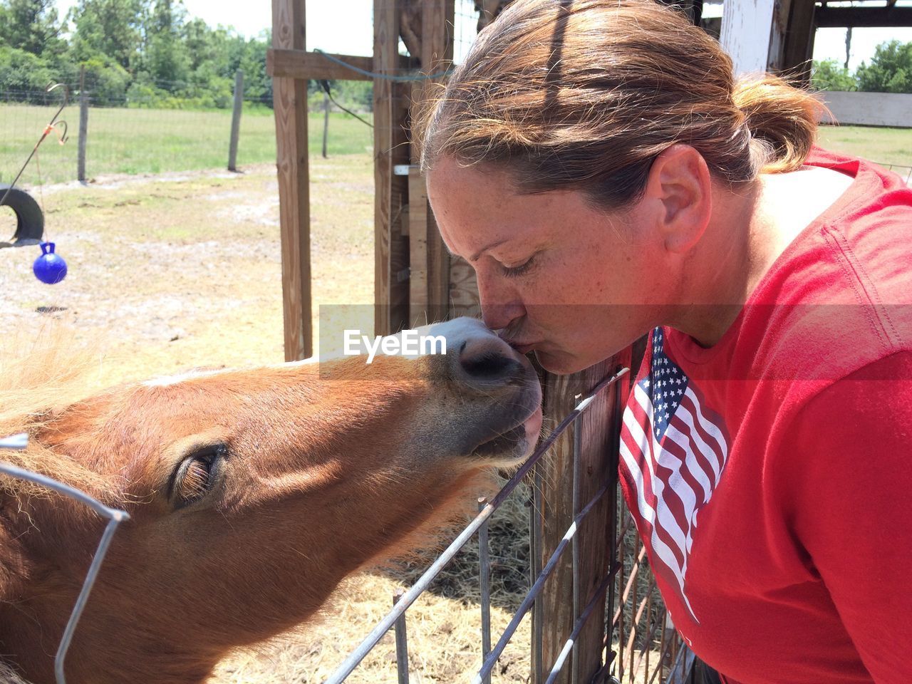 Woman kissing horse at ranch