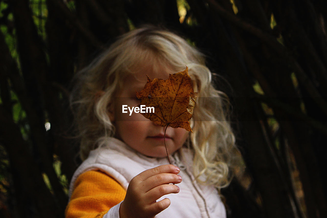 Close-up of cute girl holding leaf standing outdoors