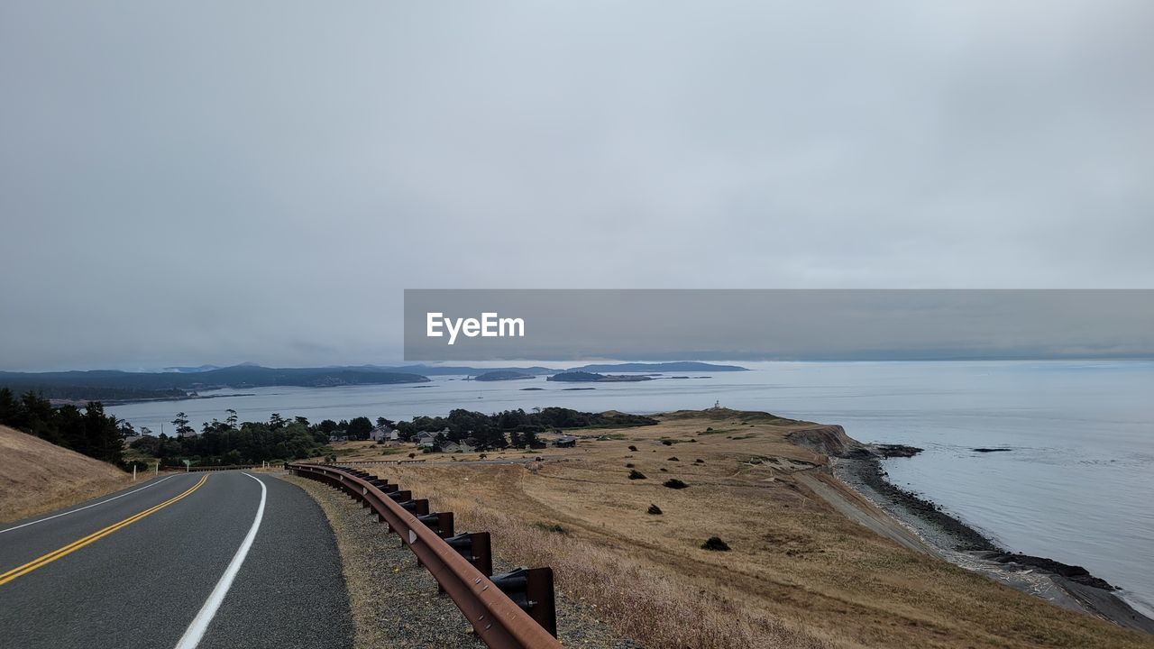 sky, horizon, sea, water, road, coast, land, cloud, beach, transportation, nature, scenics - nature, environment, beauty in nature, landscape, symbol, travel, no people, travel destinations, tranquility, the way forward, ocean, sign, coastline, shore, tranquil scene, overcast, outdoors, road marking, horizon over water, non-urban scene, day, tourism, vanishing point, dramatic sky, sand, marking, motion, morning, storm, guidance, highway, diminishing perspective, holiday, trip