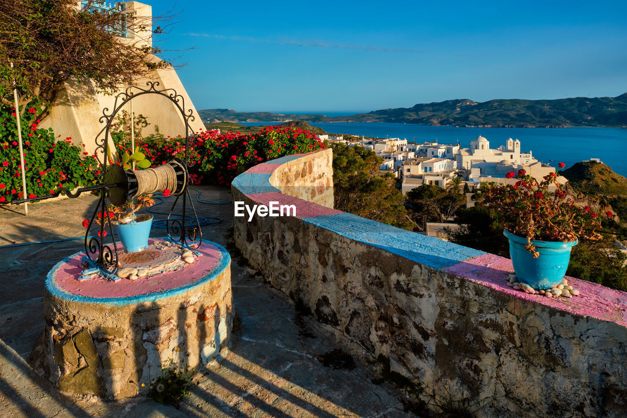 Picturesque scenic view of greek town plaka on milos island over red geranium flowers