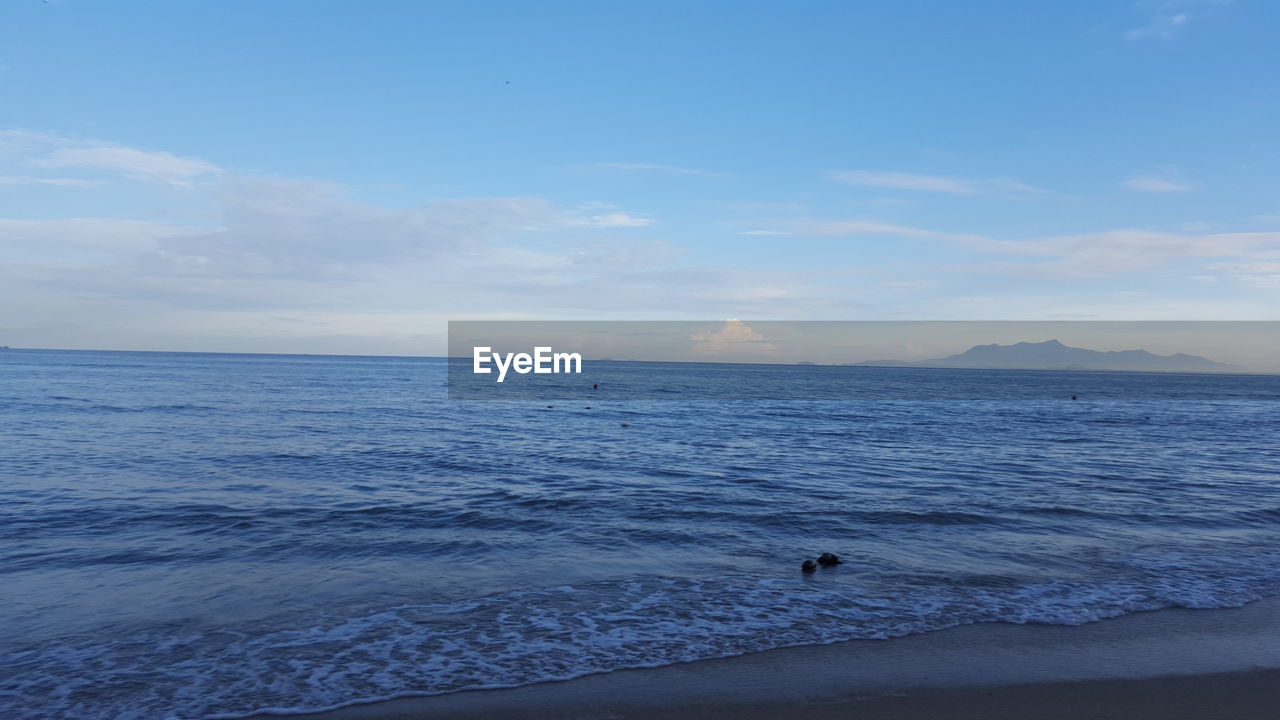 Scenic view of sea against sky with distant mountain