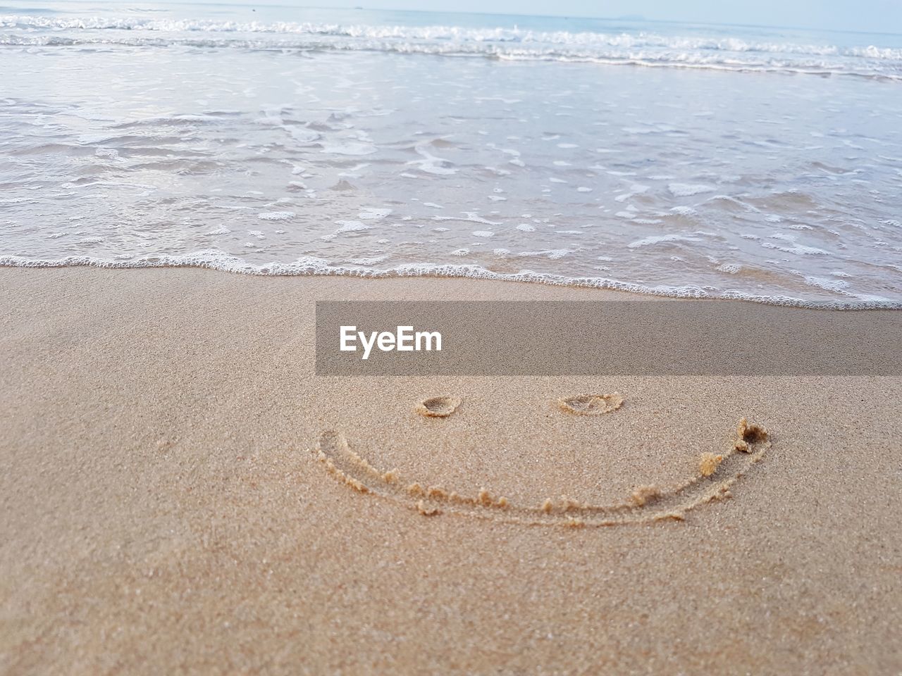 Drawing a smiley face on snady beach