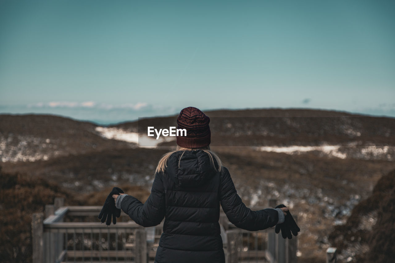 Rear view of woman looking at mountain against sky