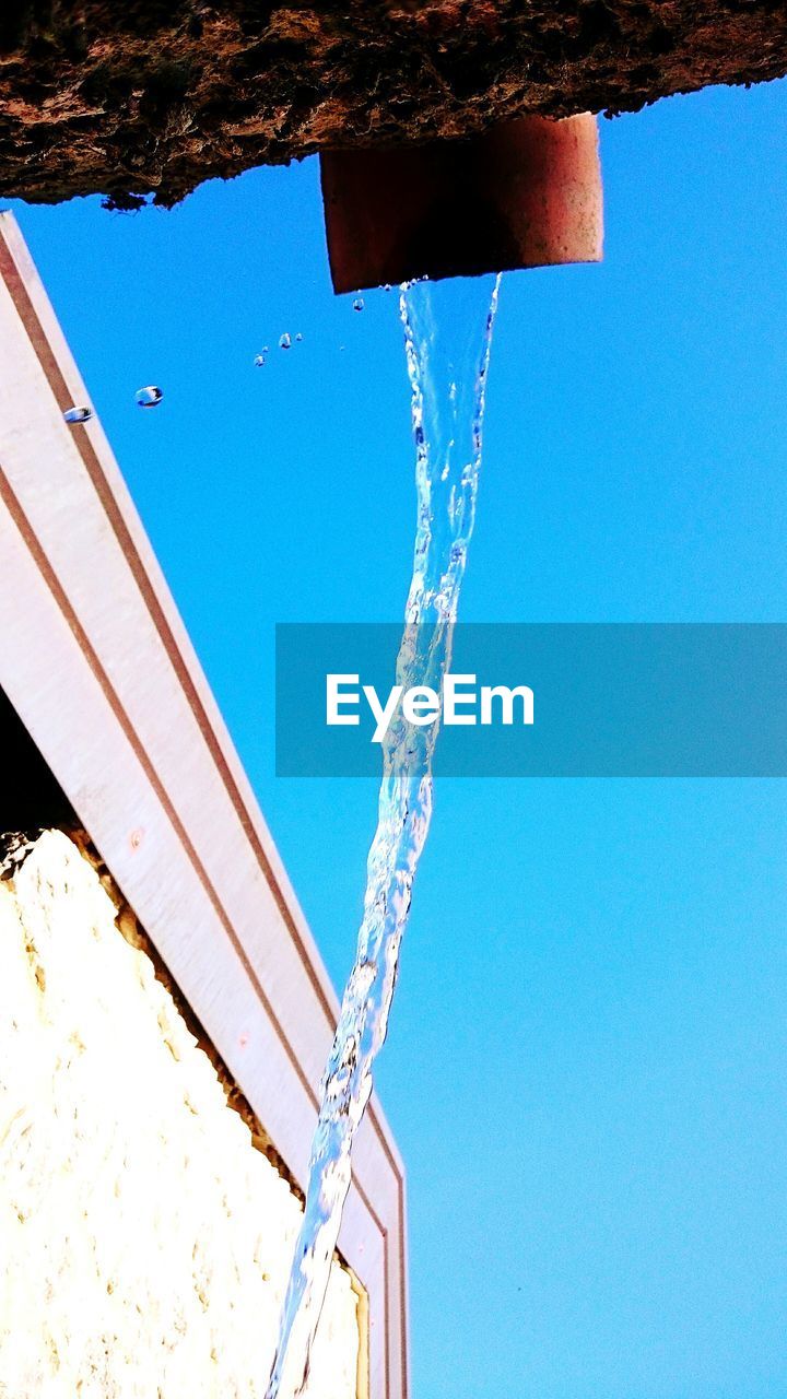LOW ANGLE VIEW OF WATER SPRAYING AGAINST CLEAR SKY