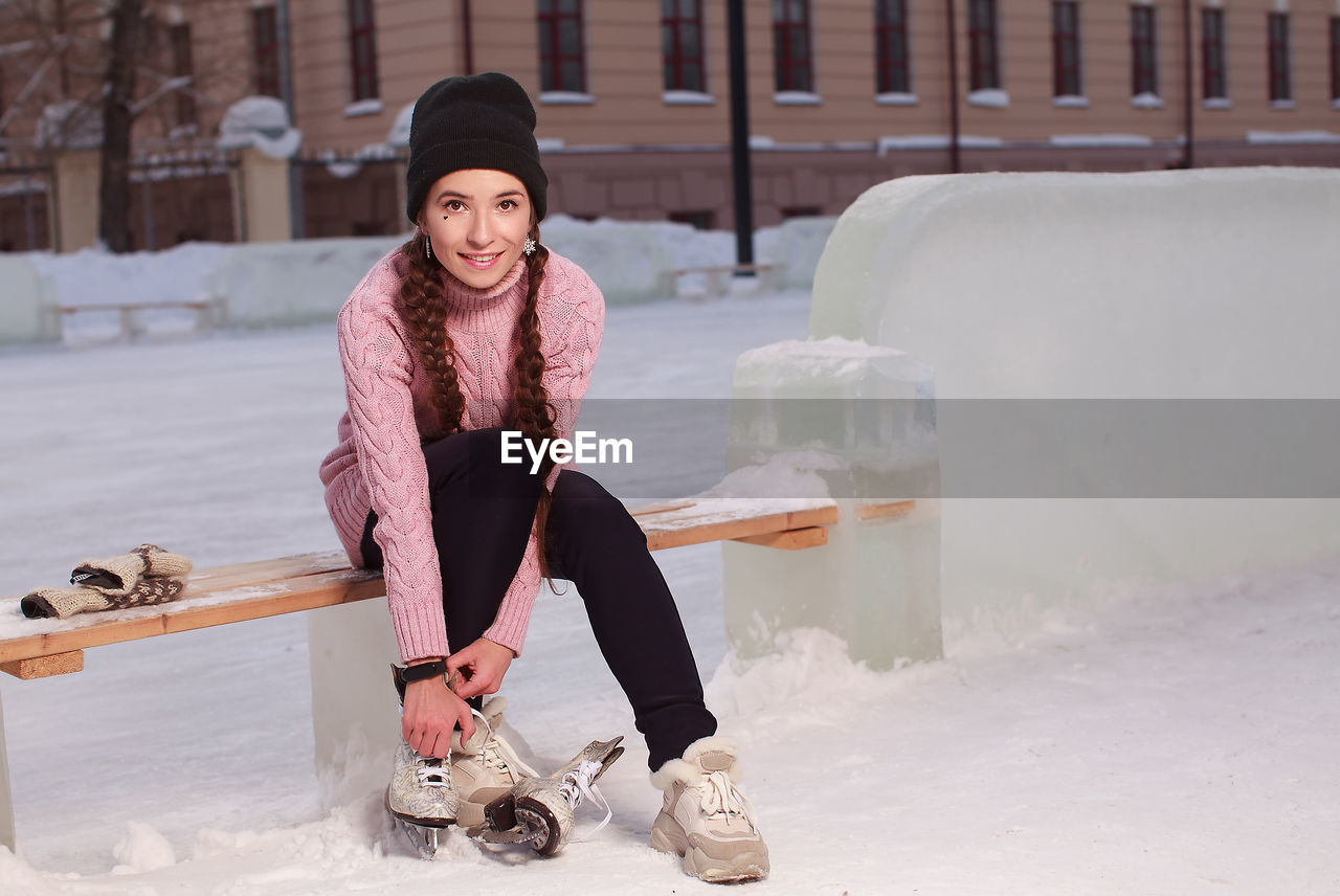 Young pretty woman putting on skates before skating