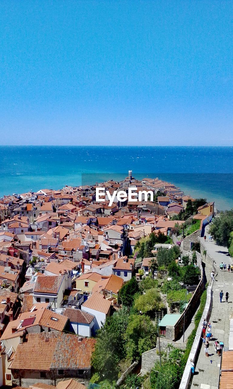 High angle view of townscape by sea against clear sky