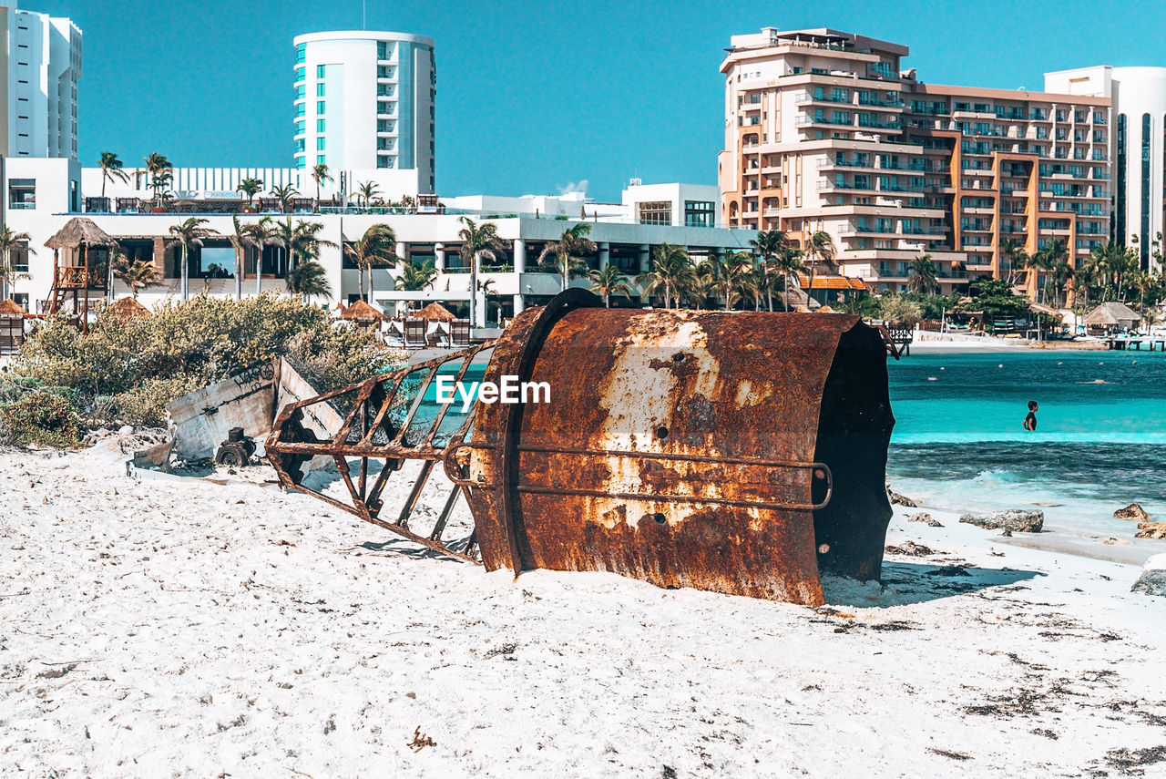 Wreckage of nautical buoy on beach with luxury hotels in background