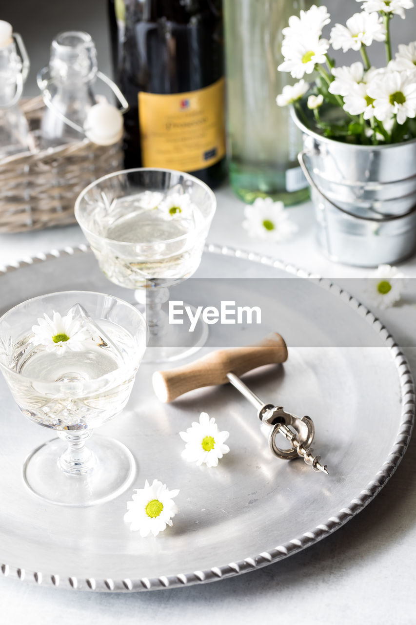 Glasses of white wine on a silver tray garnished with white flowers.