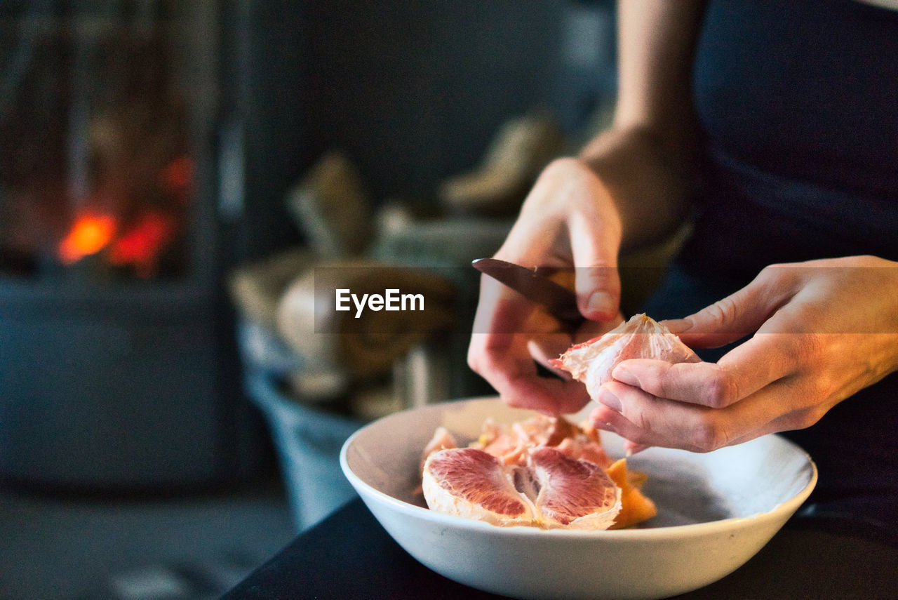 Close-up of hands preparing blood orange at cozy home