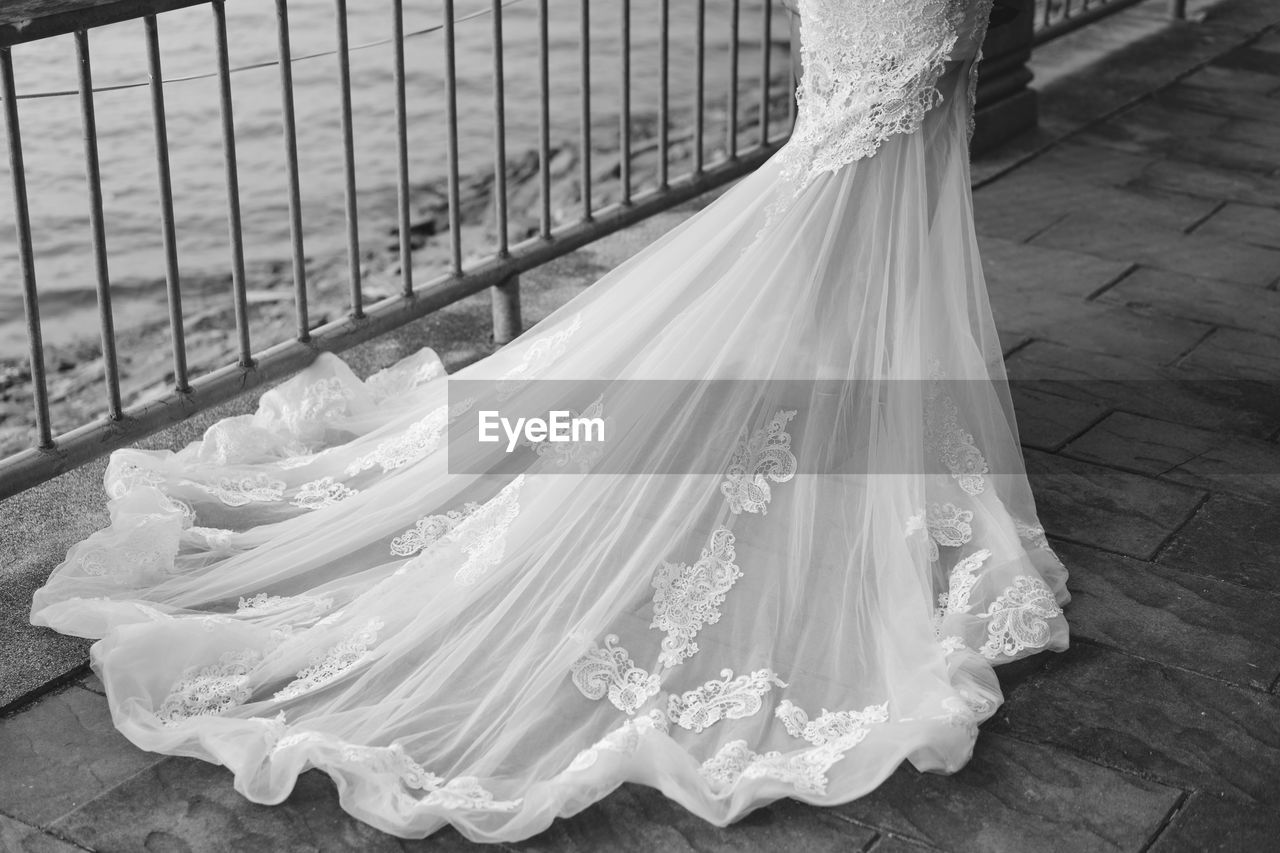 Low section of bride standing on footpath by railing